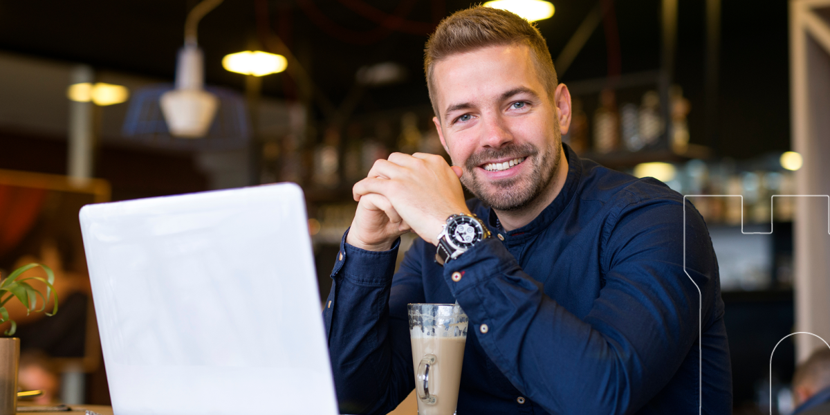 portrait-smiling-man-sitting-cafe-bar-with-his-laptop-computer 1